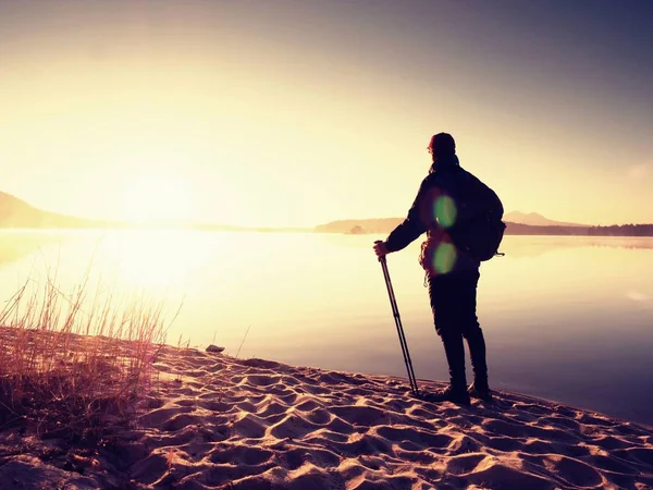 Homme randonneur en vêtements de sport sombres et avec sac à dos sportif debout sur la plage — Photo