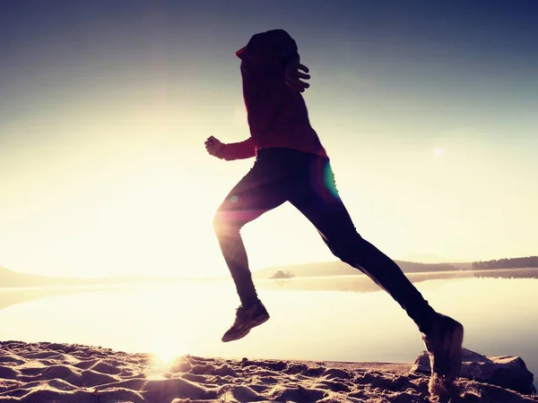 Silueta de atleta activo corriendo en la orilla del amanecer. Ejercicio de estilo de vida saludable —  Fotos de Stock