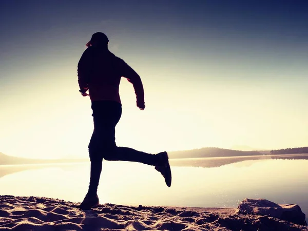 Sylwetka lekkoatletka biegacz na wschód słońca brzegu. Gimnastyka poranna zdrowego stylu życia — Zdjęcie stockowe