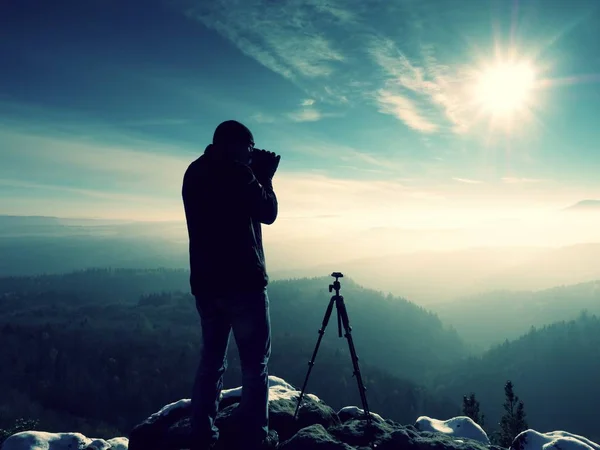 Fotógrafo estancia con cámara ind manos en trípode en roca —  Fotos de Stock