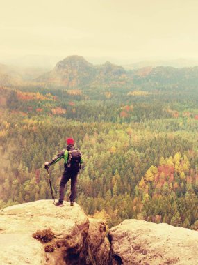 Uzun boylu uzun yürüyüşe çıkan kimse adam kırmızı kap, Polonyalılar el ve kaya kürsüye büyük sırt çantası ile. Puslu bahar 