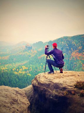 Uzun boylu yetişkin fotoğrafçı fotoğraf makinesi alarak resmi dağlar düşmek için hazırlamak. 