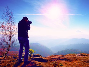 Uzun boylu adam boyunda ayna kamerayla fotoğraf çekiyorum. Dağı'nın karlı kayalık tepe. 