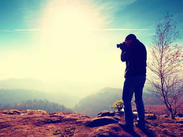 L'uomo alto sta scattando foto con una macchina fotografica a specchio sul collo. Montagna rocciosa innevata . — Foto Stock