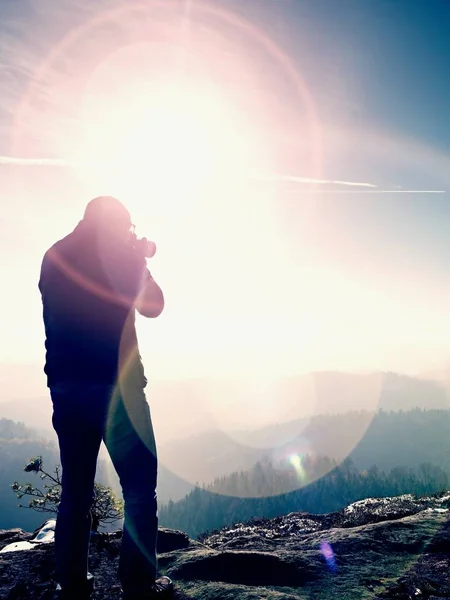 Vysoký muž je pořízení fotografie zrcadlový fotoaparát na krku. Zasněžené skalnatý vrchol hory. — Stock fotografie
