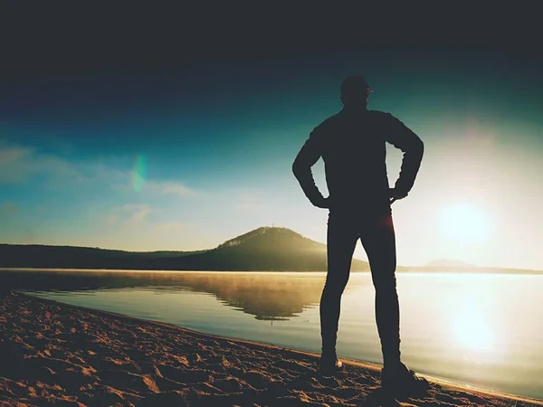 해변에 밝은 오렌지 석양에 스포츠맨 실루엣 유지. 체재 하는 남자 — 스톡 사진