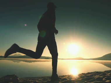 Gündoğumu kıyıda çalışan etkin atlet runner silüeti. Sabah sağlıklı yaşam tarzı egzersiz
