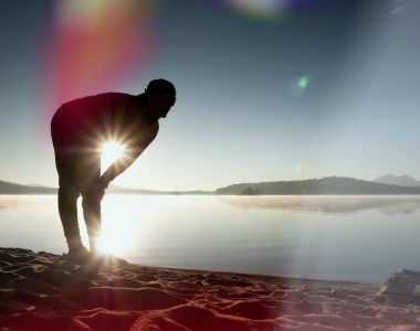 Adam atlet zaman egzersiz egzersiz okyanus plaj güneşli sabah çalıştırmak sırasında kontrol.