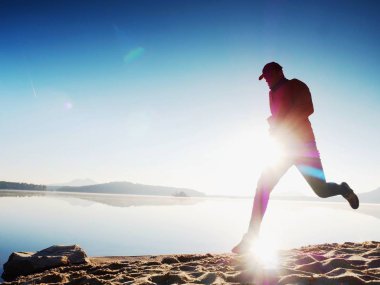  egzersiz ve göl kumsalda güneş doğarken uzanan bir adam. Sağlıklı bir yaşam tarzı. Yalnız genç fitness adam egzersiz sabah kumsalda