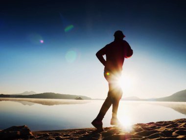  egzersiz ve göl kumsalda güneş doğarken uzanan bir adam. Sağlıklı bir yaşam tarzı. Yalnız genç fitness adam egzersiz sabah kumsalda