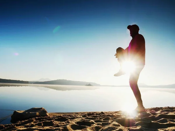 Sylwetka człowieka aktywne ćwiczenia i rozciąga się na plaży nad jeziorem o wschodzie słońca. — Zdjęcie stockowe