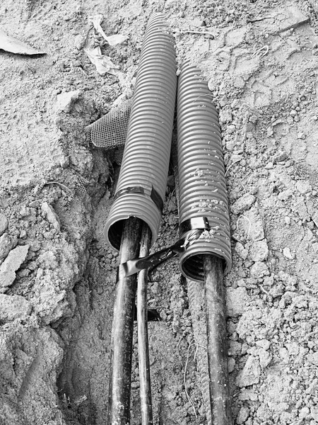 Excavation of trench  with black cables in protective HDPE tube. Lines of metallic and fiber optic wires. — Stock Photo, Image