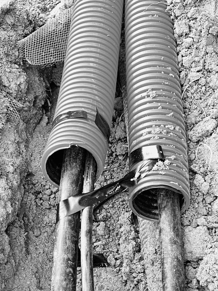Excavation of trench with black cables in protective HDPE tube. Lines of metallic and fiber optic wires. — Stock Image Excavation of trench with black cables in protective HDPE tube. Lines of metallic and fiber optic wires. Royalty Free Stock Images