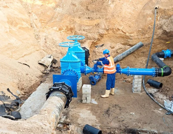 Työntekijä maan alla luistiventtiilissä, juomavesijärjestelmän uudelleenrakentaminen — kuvapankkivalokuva