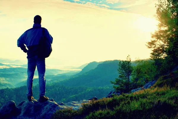 Силуэт туриста с рюкзаком. Солнечный весенний рассвет в скалистых горах. Турист со спортивным рюкзаком стоит на скалистом месте над туманной долиной . — стоковое фото