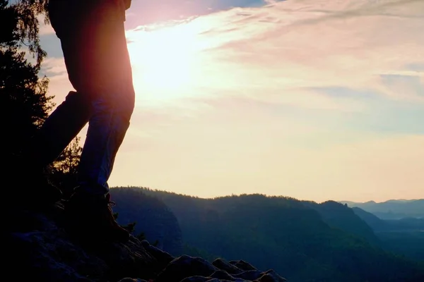 Mujer piernas excursionistas en botas turísticas de pie en la montaña rocosa pico. Sol n fondo — Foto de Stock