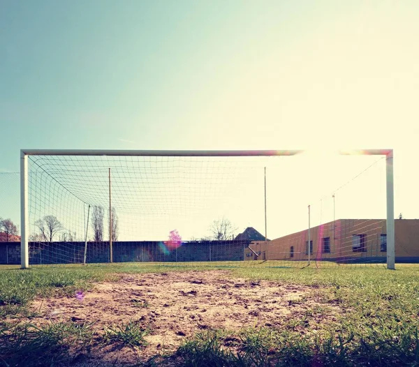 Hang bended blue yellow soccer nets, soccer football net. Grass on football playground in the background — Stock Photo, Image