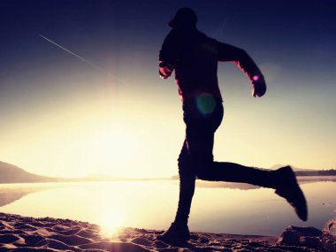 Gündoğumu kıyıda çalışan etkin atlet runner silüeti. Sabah sağlıklı yaşam tarzı egzersiz
