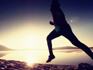 Gündoğumu kıyıda çalışan etkin atlet runner silüeti. Sabah sağlıklı yaşam tarzı egzersiz