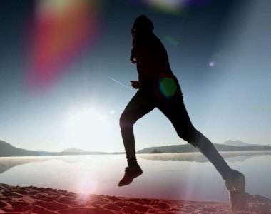 Gündoğumu kıyıda çalışan etkin atlet runner silüeti. Sabah sağlıklı yaşam tarzı egzersiz