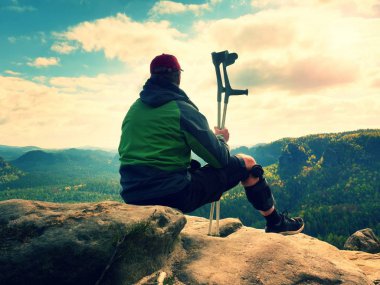 Yorgun bir adam turist sit immobilizer veya rock, zarar diz ile tıp direği tut. Açık orman manzara