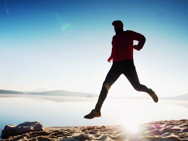 Silueta de atleta activo corriendo en la orilla del amanecer. Ejercicio de estilo de vida saludable — Foto de Stock