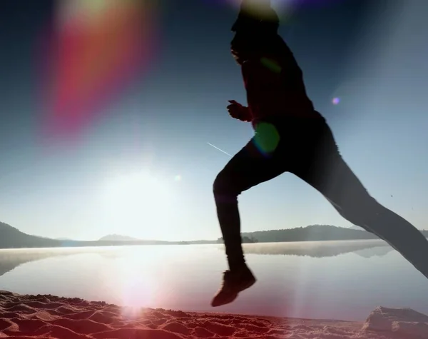 Silueta de atleta activo corriendo en la orilla del amanecer. Ejercicio de estilo de vida saludable —  Fotos de Stock