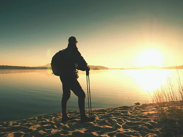 Homme randonneur en vêtements de sport sombres et avec sac à dos sportif debout sur la plage — Photo