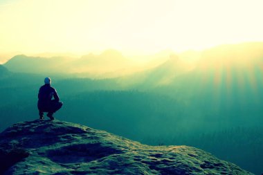 Uzun yürüyüşe çıkan kimse kayalık bir tepe üzerinde oturur ve dağlar sahne tadını çıkarın