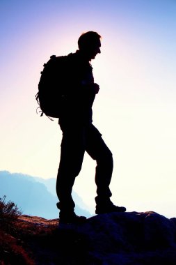 Turizm spor sırt çantası ile ayağa kayalık bakış ve puslu Vadisi feryat izlerken. Güneşli sisli gün doğumuna rocky Dağları.