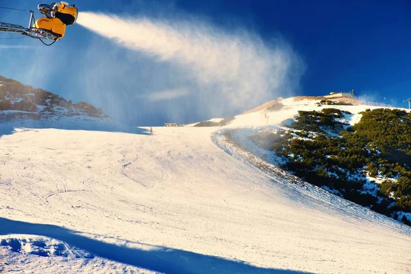 Skifahrer in der Nähe einer Schneekanone, die Pulverschnee macht. Alpen-Skigebiet. — Stockfoto