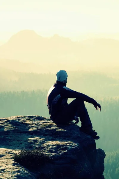 Senderista se sienta en un pico rocoso y disfrutar del paisaje de las montañas —  Fotos de Stock