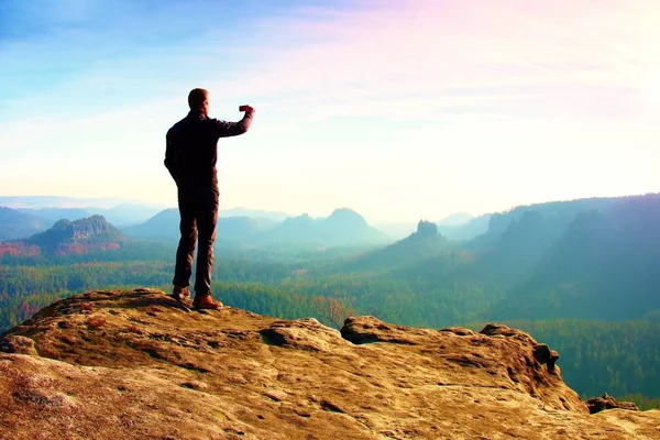 Slim turista sul bordo della roccia nel parco imperi rocciosi sta guardando sopra la nebbiosa e nebbiosa valle del mattino al sole — Foto Stock