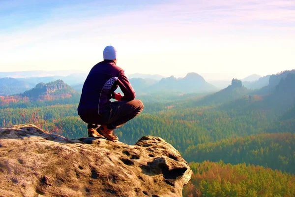 在黑色运动装的年轻男子是坐在悬崖边上，期待迷雾笼罩的山谷贝娄 — 图库照片