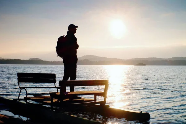 Turista alto con mochila a pie en la playa en barco a pedal en la puesta del sol. Otoño en el mar — Foto de Stock