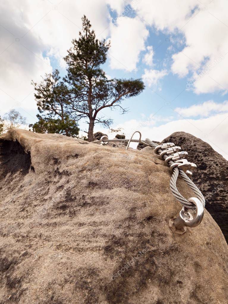 Iron twisted rope stretched between rocks in climbers patch via ferrata.  Rope fixed in rock