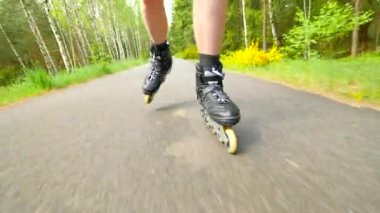 Ormanın içinde düzgün asfalt üzerinde açık paten. Açık tenli adam ayakları hızlı hareket satır içi çizme görünümüne kadar kapatın.