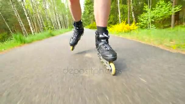 Patinaje en línea al aire libre sobre asfalto liso en el bosque. Vista cercana a la piel clara hombre piernas movimiento rápido de botas en línea . — Vídeos de Stock