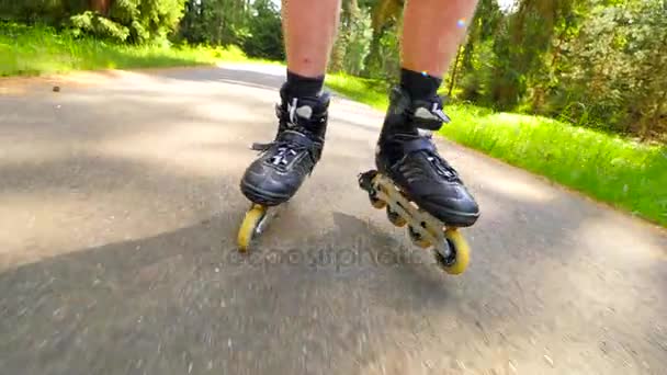 インライン スケート森で滑らかなアスファルトの上を開始します。光の肌男足インライン ブーツの素早い動きにビューをクローズ アップ. — ストック動画