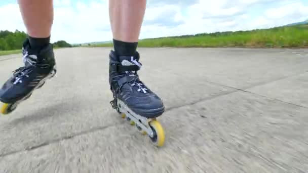 Mans benen rolschaatsen op de asphal. Close-up te snelle beweging van inline laarzen. — Stockvideo