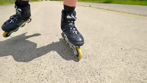 Mans benen rolschaatsen op de asphal. Close-up te snelle beweging van inline laarzen. — Stockvideo