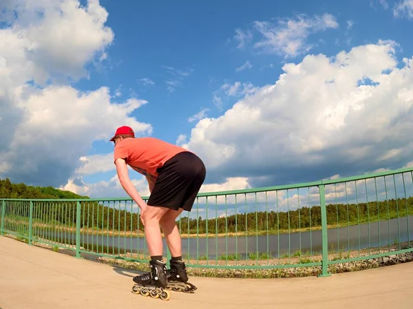 Widok z tyłu inline Skater w czerwoną koszulkę i czarne spodnie, jazda na łyżwach na moście. Odkryty na rolkach — Zdjęcie stockowe