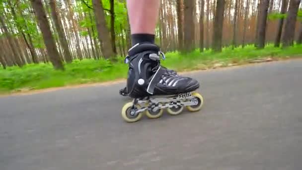 Vue latérale rapprochée de la jambe de patin à roues alignées. Homme facile à monter sur la voie lisse dans le parc forestier. Vue rapprochée pour un mouvement rapide des bottes en ligne . — Video