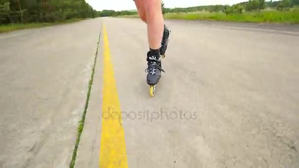 Shuffle inline skating on way in pine forest. Mans legs roller skating on the asphalt in hot summer day. Close up view to quick shuffle movement of four wheels inline boots. — Stock Video