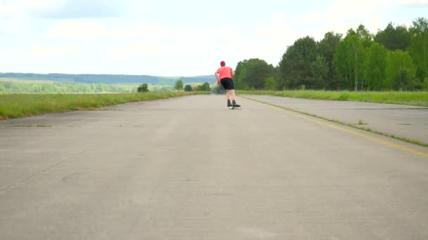 Practica bien el patinador disfrutando de la mezcla en línea. El hombre con gafas de sol, camiseta roja clara y pantalones negros transfiere fácilmente peso de pierna a pierna y mira a su alrededor. Bonito día soleado de verano en el parque de skate natural — Vídeos de Stock