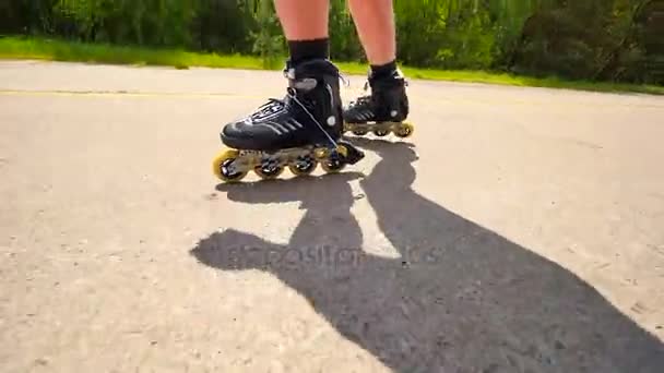 Zijaanzicht zeer dichtbij te werken inlineskates. Gemakkelijk schaatsen op het gladde asfalt. Close-up te snelle beweging van zwarte vier wielen inline laarzen. — Stockvideo