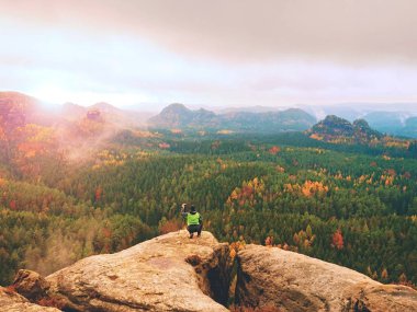 Uzun yürüyüşe çıkan kimse ile fotoğraf makinesi tripod üzerinde kayalık Zirvesi resimden alır. Yalnız fotoğrafçı kenar fotoğraf peyzaj
