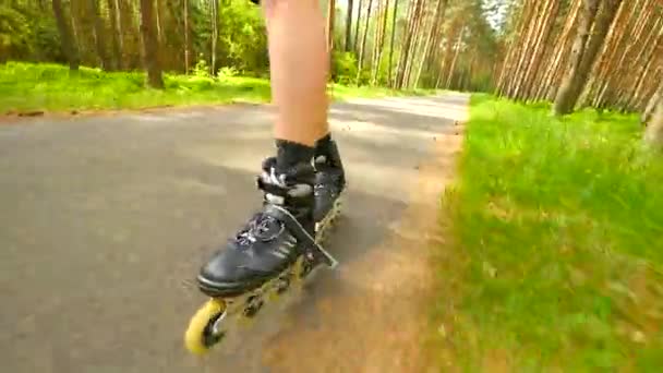 Baraja patinaje en línea en camino en el bosque de pinos. Patines para hombre patinaje sobre el asfalto en el caluroso día de verano. Vista de cerca al movimiento rápido de la baraja de cuatro ruedas botas en línea . — Vídeo de stock