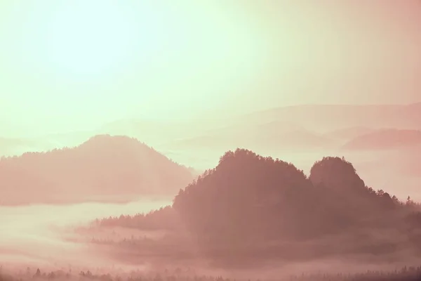 Misty landscape with fog between hills and orange sky within sunrise — Stock Photo, Image