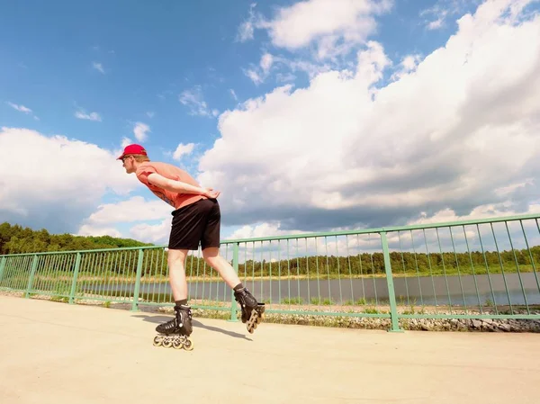 Blick von hinten auf Inline-Skater in rotem T-Shirt und schwarzer Hose, die auf der Brücke Schlittschuh laufen. Inlineskating im Freien — Stockfoto